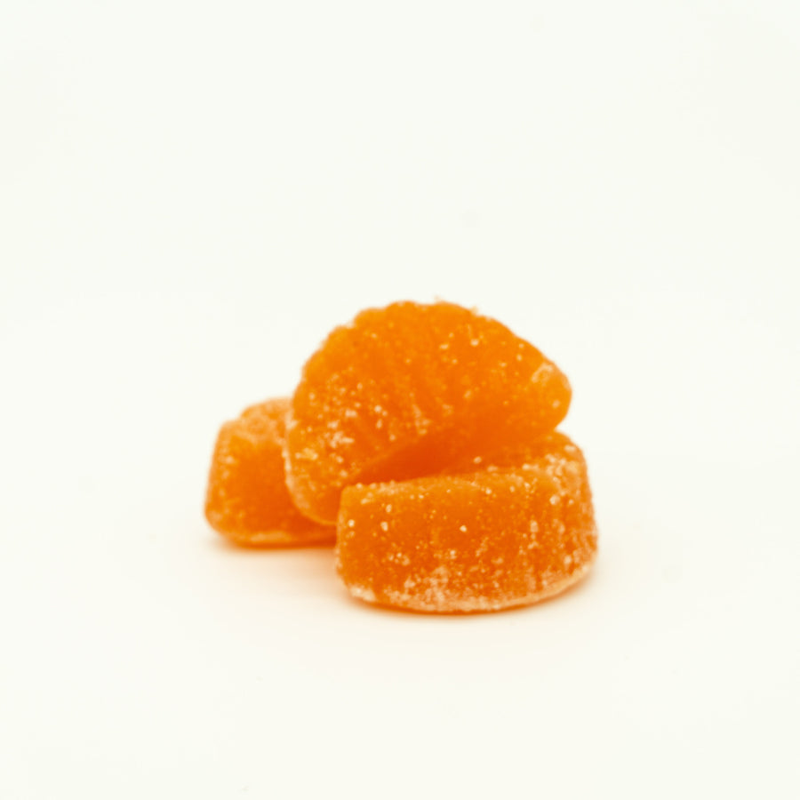 Three orange gummy candies on a white background